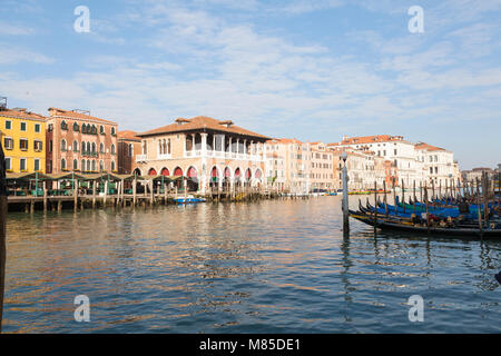 Lever du soleil sur le Grand Canal et le marché aux poissons du Rialto, San Polo, Venise, Vénétie, Italie avec deux gondoliers dépose des panneaux sur leurs bateaux amarrés à Banque D'Images