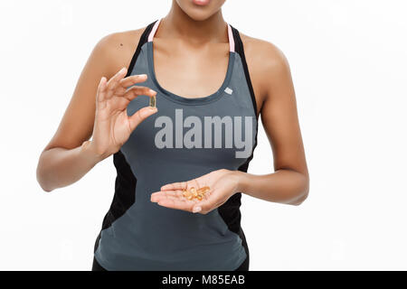 Concept de remise en forme et en bonne santé - Closeup portrait of beautiful African American prendre une pilule d'huile de foie de morue. Isolé sur fond blanc studio. Banque D'Images