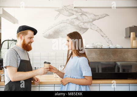 - Concept d'affaires Café smart jeune barman barbu aime parler et donner à emporter, tasse de café à la jolie client. Banque D'Images