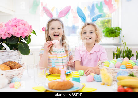 Petit-déjeuner de Pâques en famille. Enfant avec oreilles de lapin à la table décorée avec des oeufs panier, chick et lapin le matin de Pâques. Chasse aux oeufs et les repas pour enfants. Sp Banque D'Images