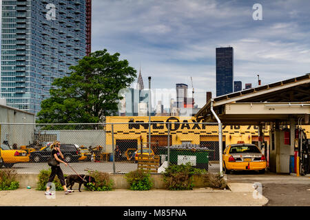 Une femme qui passe devant un taxi jaune New York qui dessert un garage et une station-service à long Island City, Queens, New York Banque D'Images