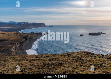 Vue sur la mer à partir de piles de Reynisdrangar Dyrholaey, de l'Islande à l'océan, les vagues, la plage de sable volcanique noir, les falaises, les montagnes, et les oiseaux en premier plan Banque D'Images