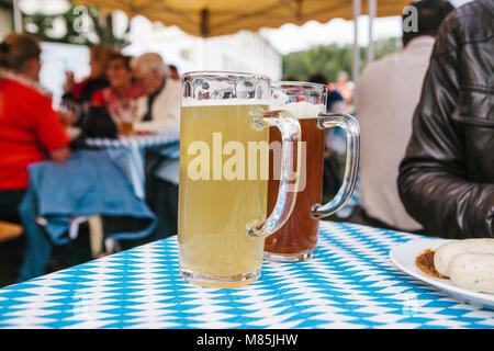 La célébration de la traditionnelle fête de la bière Oktoberfest allemand appelé. Deux tasses avec une lumière et obscurité stand de bières sur la table. Dans l'arrière-plan, blurre Banque D'Images