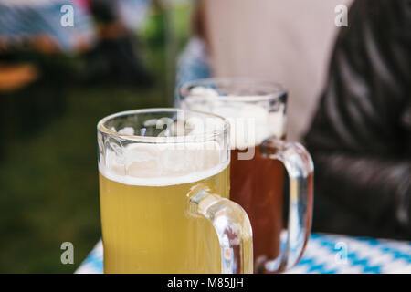 La célébration de la traditionnelle fête de la bière Oktoberfest allemand appelé. Deux tasses avec une lumière et obscurité stand de bières sur la table. Banque D'Images