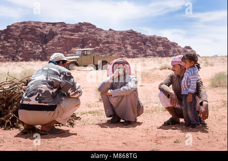 Un groupe de Bédouins accroupie avec petite fille dans le désert de Wadi Rum en Jordanie. Banque D'Images