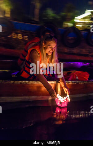 Une happy female tourist abaisse une lanterne à bougie flottante dans l'eau à Hoi An, Vietnam Banque D'Images