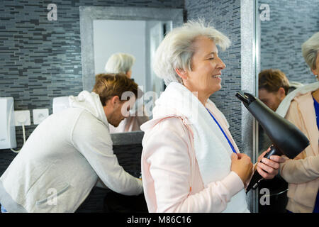 A senior woman drying her hair elle-même Banque D'Images