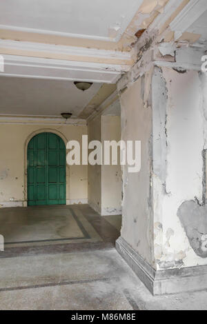 L'extérieur de l'hôtel abandonné un vieux avec un mur de déroulage et de moule. L'ancienne porte verte avec de vieux lustres au plafond. Banque D'Images