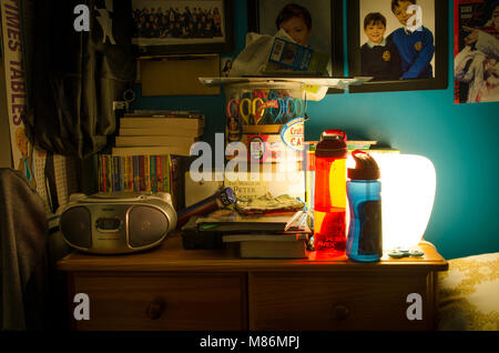 Une commode de chevet dans une chambre du garçon, éclairé par une lampe de nuit. Banque D'Images