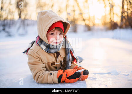 Portrait of a smiling boy lying on frozen lake Banque D'Images