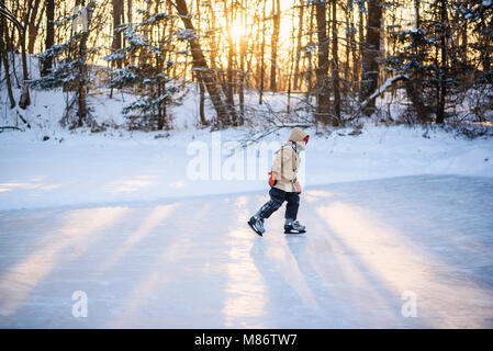Boy le patin à glace sur un lac gelé Banque D'Images