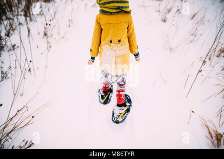 Fille qui marche dans la neige raquettes Banque D'Images