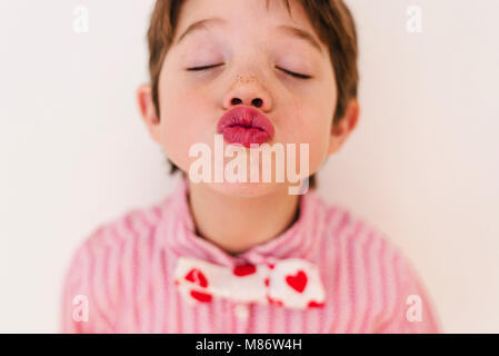 Portrait d'un garçon portant une chemise et un noeud papillon avec des coeurs soufflant un baiser Banque D'Images