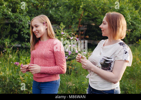 Mère et fille cueillette des fleurs dans un jardin Banque D'Images