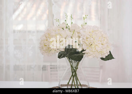 Un bouquet de fleurs blanches dans un bocal en verre sur un fond blanc Banque D'Images
