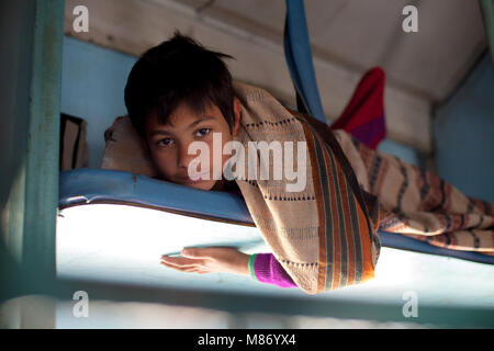 Jeune garçon indien portant sur des ministère, voyager en train à la recherche d'appareil photo. Il porte des sweather violet et il est couvert avec belle fine Banque D'Images