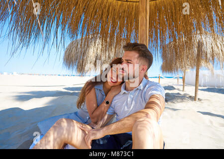 Jeune couple câlin dans une plage, sous un parasol à l'été Banque D'Images