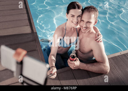 Vue de dessus sur relaxed couple en tenant vos autoportraits in swimming pool Banque D'Images
