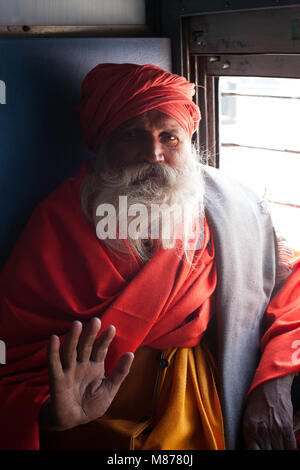 Portrait d'un vieil Indien sadhu - saint homme voyageant en train, assis à côté d'envoyer ses bénédictions de la fenêtre avec sa main droite. Il porte l'orange Banque D'Images