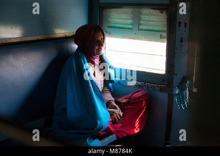 Un portrait d'une femme indienne assis les jambes croisées en train la prochaine fenêtre de chat et les avoir détendu et souriant visage amical d'expression. Elle Banque D'Images