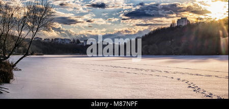 Soirée soleil illumine les nuages sur la rivière gelée (Ukraine, Kiev, le sud du fleuve Bug) Banque D'Images