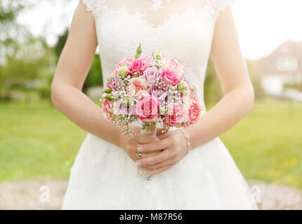 Une mariée en robe blanche tenant un bouquet de mariage, pas de visage Banque D'Images