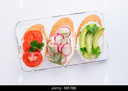 Mini-sandwiches au fromage à la crème, légumes et de l'avocat. Choix de sandwichs sur fond blanc, vue du dessus. Mise à plat Banque D'Images