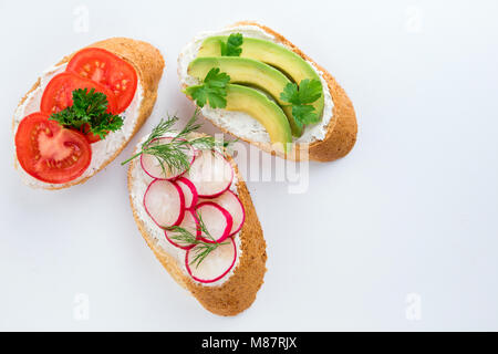 Mini-sandwiches au fromage à la crème, légumes et de l'avocat. Choix de sandwichs sur fond blanc, vue du dessus. Mise à plat Banque D'Images