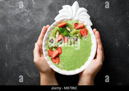 Femme tenant un bol à smoothie kiwi, les épinards, les fraises. Femmes avec de petits fruits smoothie vert, vue du dessus Banque D'Images