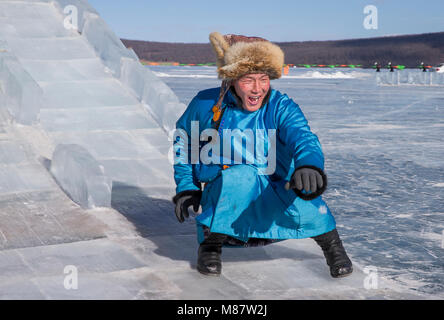 Hatgal, Mongolie, 4e mars 2018 : mongolian homme vêtu de vêtements traditionnels sur la glace d'un lac Khuvsgul, descendant un toboggan de glace Banque D'Images