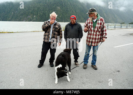 Trois amis et les résidents de la ville de Hyder, Alaska, chatter sur le bord de la mer, ci-dessous les fjords de la canal Portland, USA. Banque D'Images