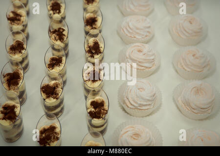 Ensemble de desserts tiramisu dans des verres et blanc zephyr en rangées sur la table Banque D'Images