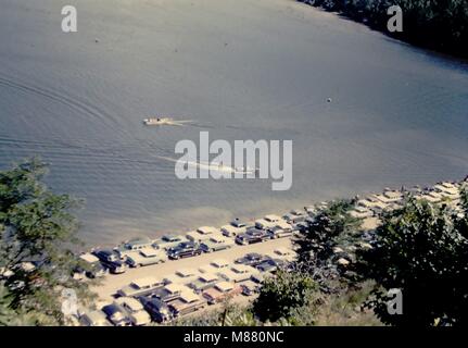 Prises d'une collection de diapositives qui ont été prises en vacances il y a des années. Classic cars alignés par le lac où les sports d'eau. Spectateurs alignés le long côté de la montagne qui a entouré le lac. Banque D'Images