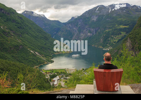 L'homme regardant la vue de Flydalsjuvet lookout à Geiranger - le Geirangerfjord, village de Geiranger et un bateau de croisière de quitter le port Banque D'Images