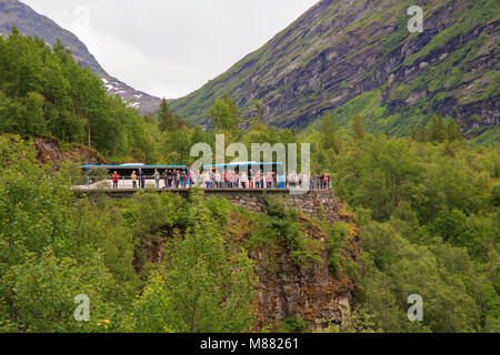 Les bus en stationnement et un groupe de touristes à la recherche d'un bout à l'avis de Geiranger à partir d'un point d'observation de la montagne Banque D'Images