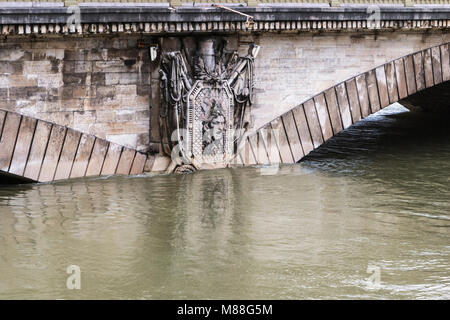 Pierre partiellement submergé de secours en tête de Méduse militariste armoiries sur le pont des Invalides à Paris en janvier 2018 inondation. Banque D'Images