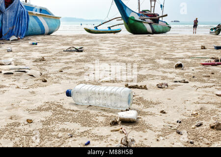 Close up vide bouteille de plastique utilisé et autres déchets jetés à la mer plage sur fond est bateaux de pêche. Banque D'Images