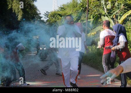 Bogor, Indonésie. Mar 16, 2018. Les participants courent à travers les nuages de poudre colorés jetés par des bénévoles au cours de la 'BIG 4K Color Run' organisé par l'Agence d'information géospatiale (BIG) Le 16 mars 2018 à Cibinong, Java ouest, Indonésie.Les participants ont couvert de poudre de craie de couleur a pris part à la course qui a été inspiré par l'Indian Holi Festival. Credit : Risa/Krisadhi Pacific Press/Alamy Live News Banque D'Images