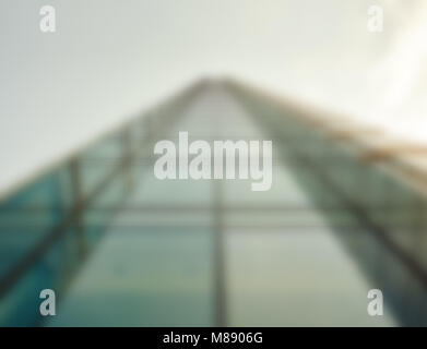 Defocused low angle droit d'un gratte-ciel moderne en verre s'élevant jusqu'au ciel dans le quartier commerçant d'une ville Banque D'Images