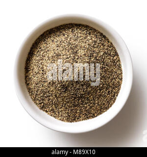 Poivre noir moulu finement dans Bol en céramique blanc isolé sur blanc de ci-dessus. Banque D'Images