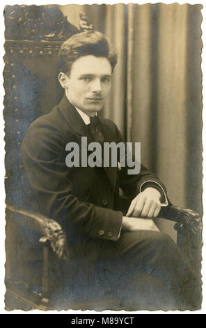 Meubles anciens c1920 photo, homme âgé de 25 ans dans une bibliothèque de fantaisie président. SOURCE : photographie originale. Banque D'Images