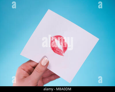 Mise à plat. Vue d'en haut. Main de fille écrit Lettre d'amour sur Saint Valentines Day. Carte postale avec la main en forme de lèvres rouge figure. Femme attirer kiss sur une carte postale pour le 14 février fêtes Banque D'Images