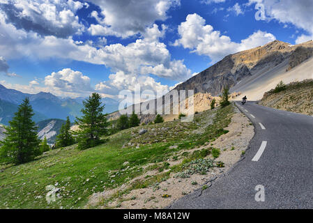 Un motard dans la distance vue arrière sur le trajet dans paysage de montagne sous ciel nuageux ciel bleu Italie Piémont Alpes vers juin 2015 Banque D'Images