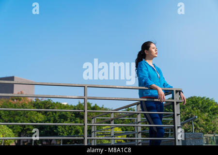 Femme Fitness runner se détendre après l'exécution de la ville et de l'extérieur. Girl leaning on fence et les yeux dans le lointain. Banque D'Images