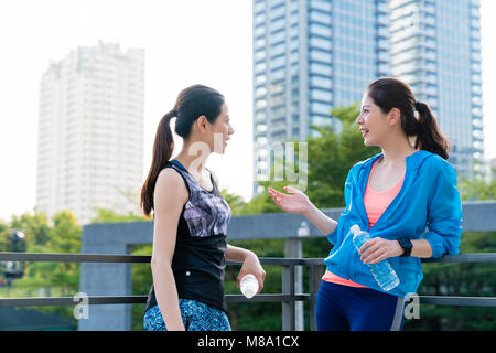 Deux coureurs des femmes en prenant une pause à discuter avec l'arrière-plan de la ville après avoir exécuté le matin. Banque D'Images