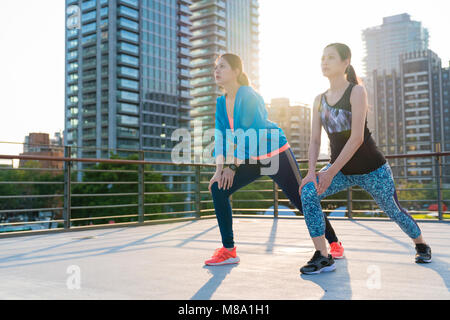 Dames l'étirement des jambes après l'exécution de la formation dans le soleil au coucher du soleil. Pour obtenir dans la forme, l'espérance de vie en concept. Banque D'Images