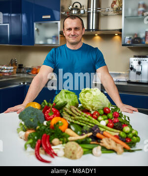 Homme avec une grande variété de légumes, prêts à être cuisinés Banque D'Images
