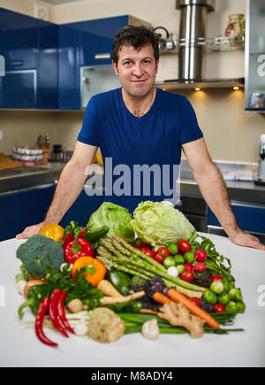 Homme avec une grande variété de légumes, prêts à être cuisinés Banque D'Images