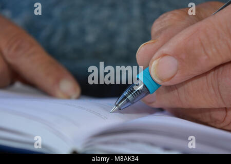 Man écrit dans un journal intime, close-up de stylo à la main, selective focus on nib Banque D'Images