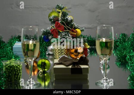 Arrière-plan flou abstrait:Noël ou Nouvel An. Dans les verres de champagne avec des bougies, panettone et cadeau avec noeud en satin rouge. Copier-espace. Conce festive Banque D'Images